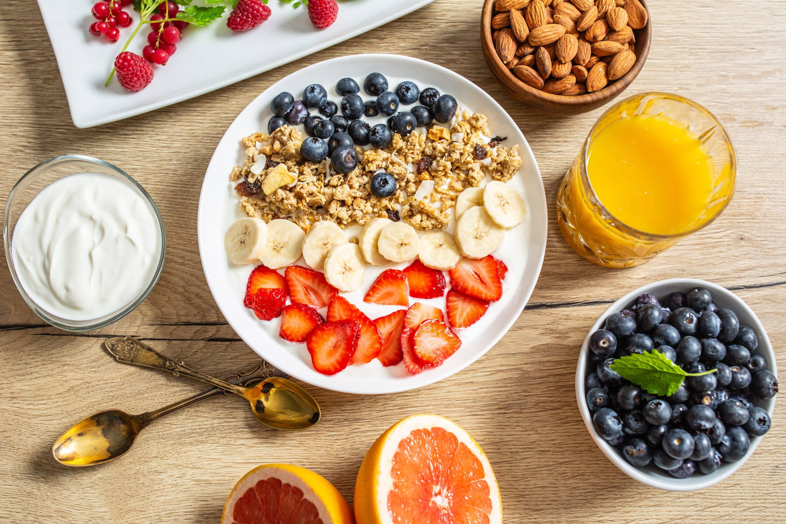 Healthy breakfast served with plate of yogurt muesli blueberries strawberries and banana.